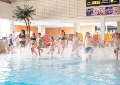 mehrere Kinder am Beckenrand, auf dem Weg ins Becken